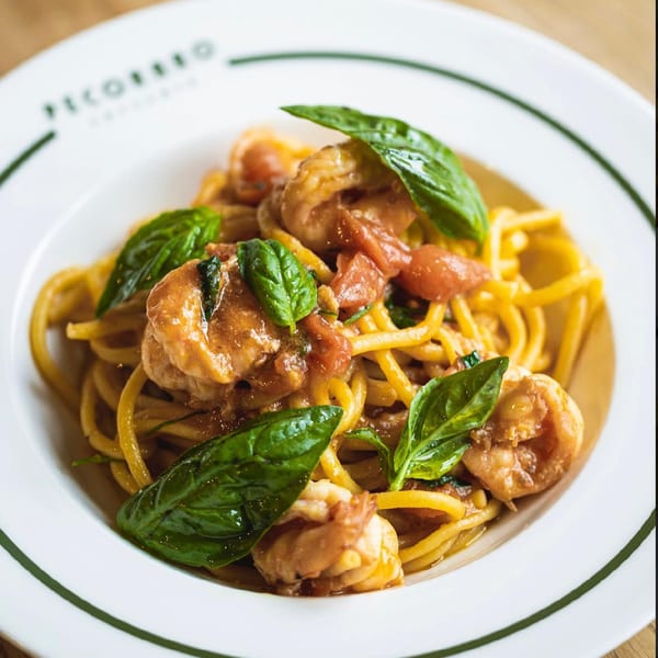 Pecoraro Latteria's shrimp pasta with fresh basil and cherry tomatoes in a white bowl.