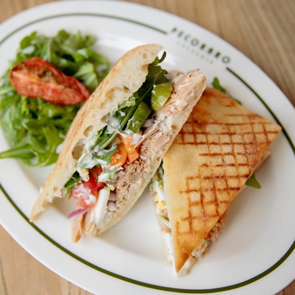 Grilled Italian panini with tuna, arugula, tomatoes, and sauce, served with a side salad.